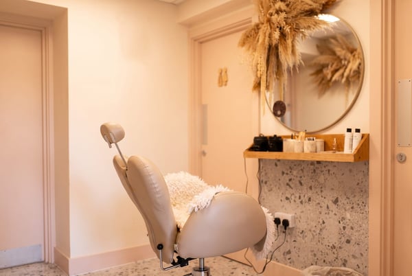 The brow treatment area at NU Beauty, with an adjustable chair, round mirror and a soft styling shelf, ready for a brow lamination