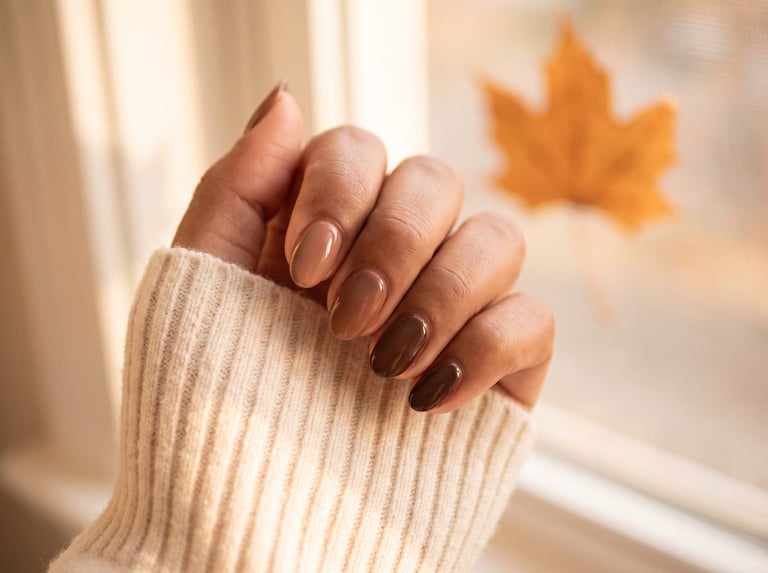 Autumn 2026 nail idea: A hand with short glossy espresso-brown almond nails against a cream knit sleeve
